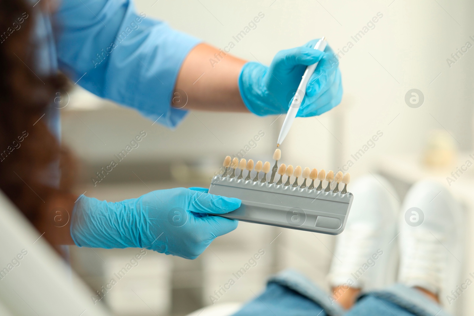 Photo of Doctor and patient choosing shade on teeth color palette in clinic, closeup. Dental veneers