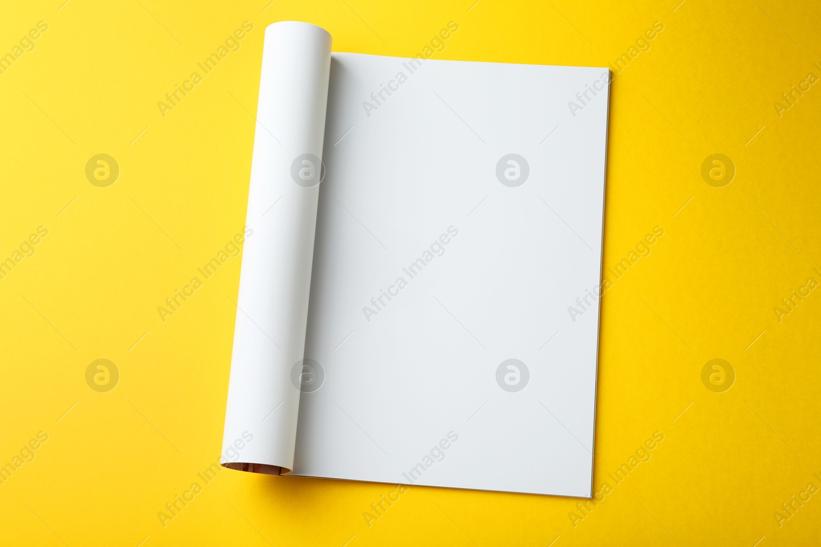 Photo of Open magazine with blank page on yellow background, top view. Mockup for design