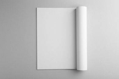 Open magazine with blank page on grey background, top view. Mockup for design