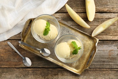 Photo of Scoops of melon sorbet with mint in glass dessert bowls, fresh fruit and spoons on wooden table, flat lay