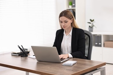 Banker using laptop at wooden table in office