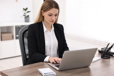 Banker using laptop at wooden table in office