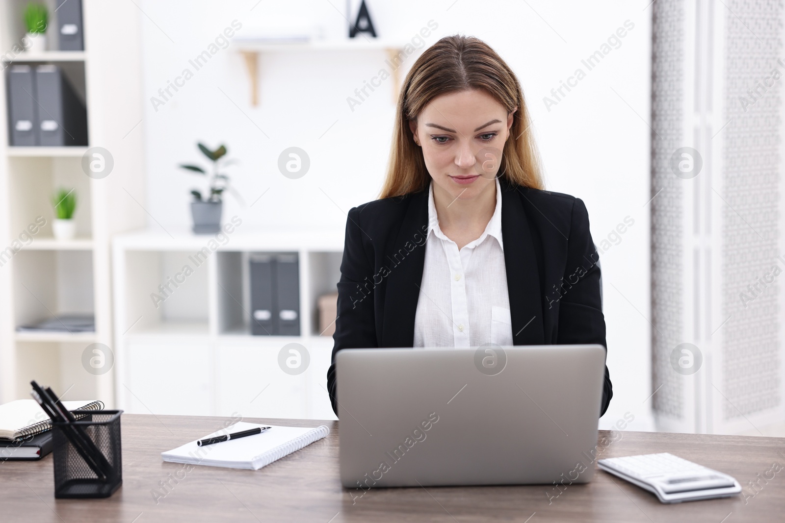 Photo of Banker using laptop at wooden table in office