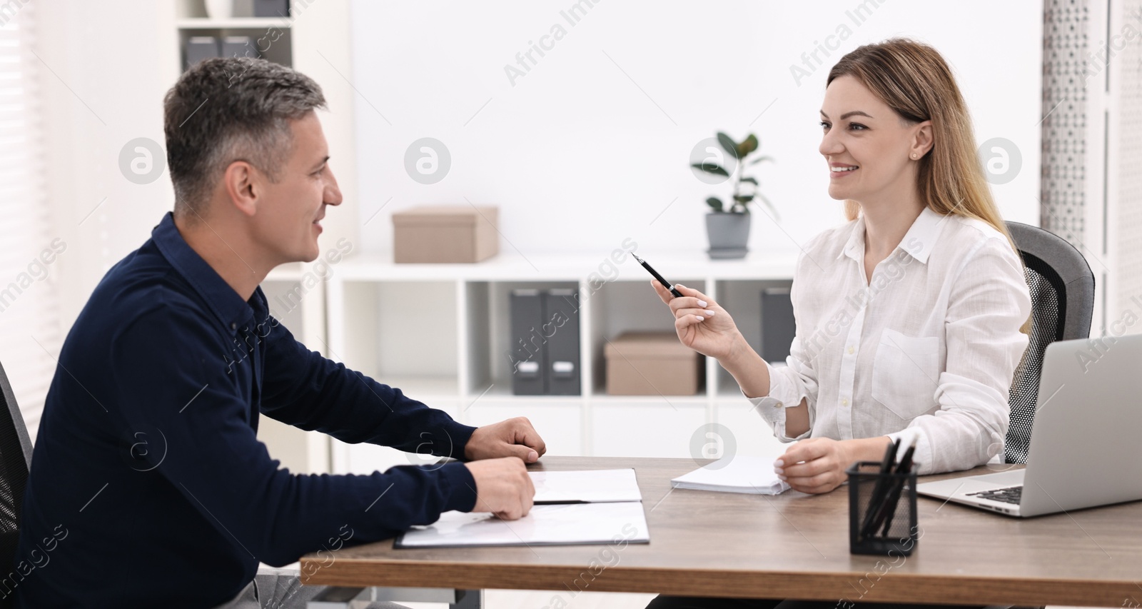 Photo of Banker working with client at wooden table in office