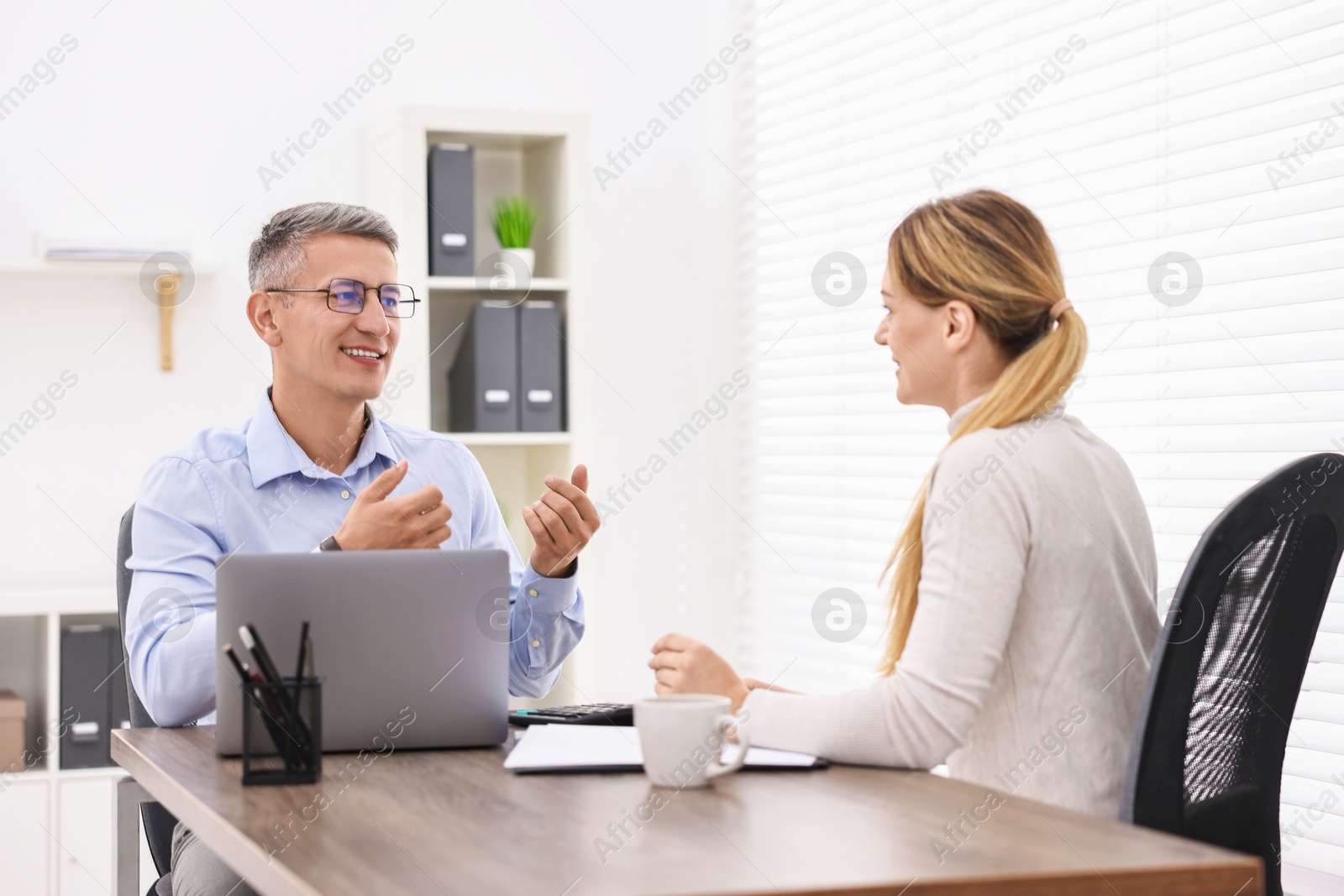 Photo of Banker working with client at table in office