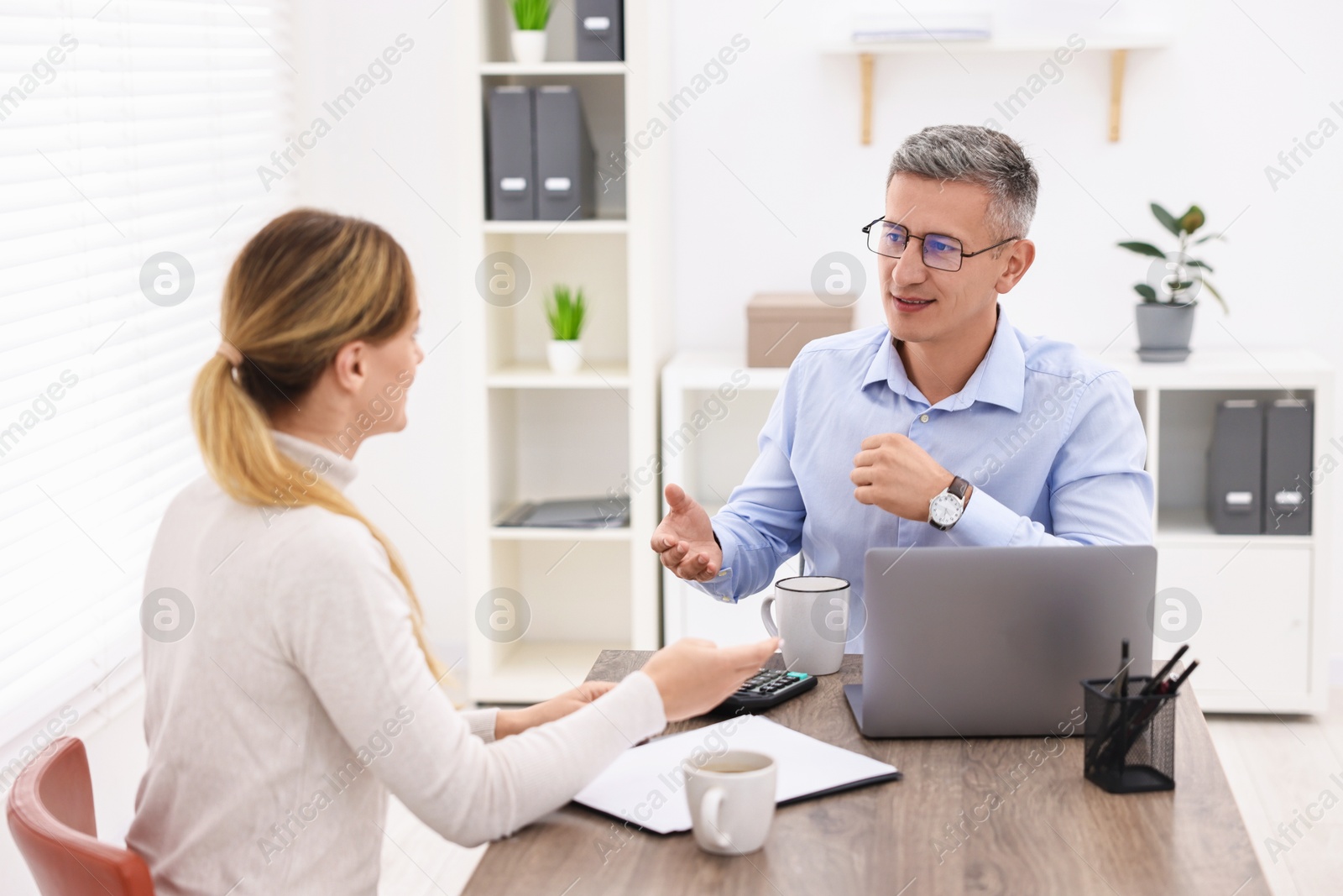 Photo of Banker working with client at table in office