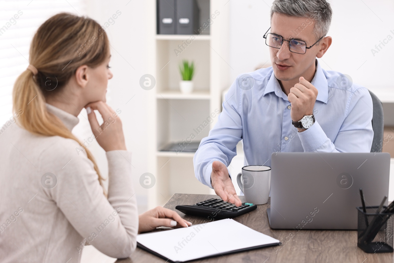 Photo of Banker working with client at table in office