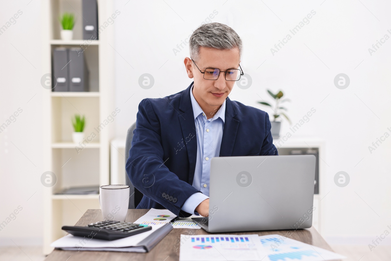 Photo of Banker using laptop at wooden table in office