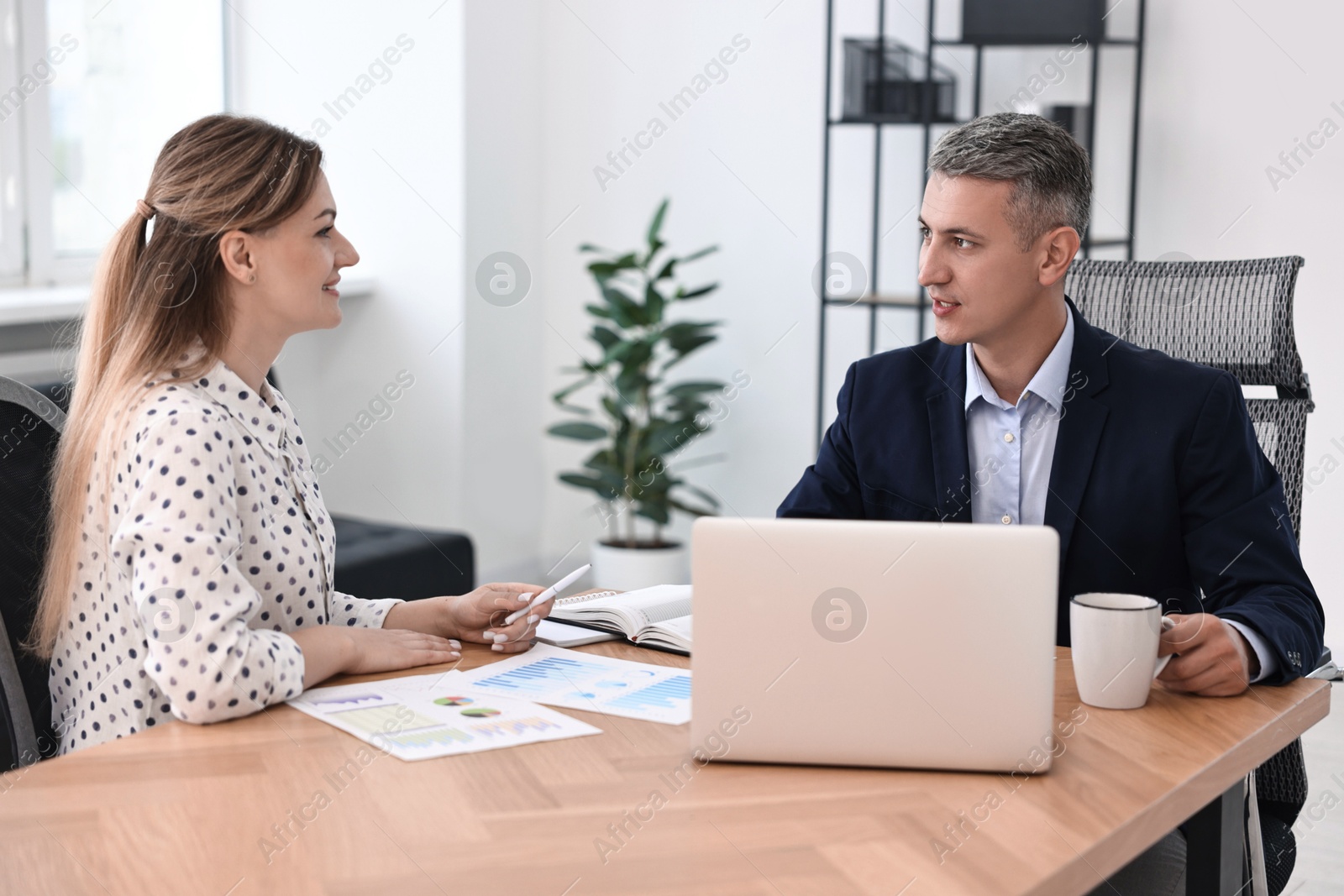 Photo of Banker working with client at wooden table in office