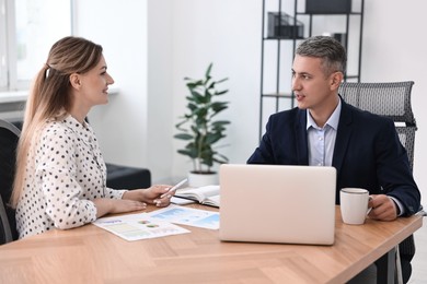 Photo of Banker working with client at wooden table in office