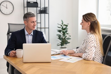 Photo of Banker working with client at wooden table in office