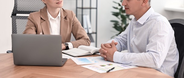 Banker working with client at wooden table in office