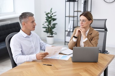 Banker working with client at wooden table in office