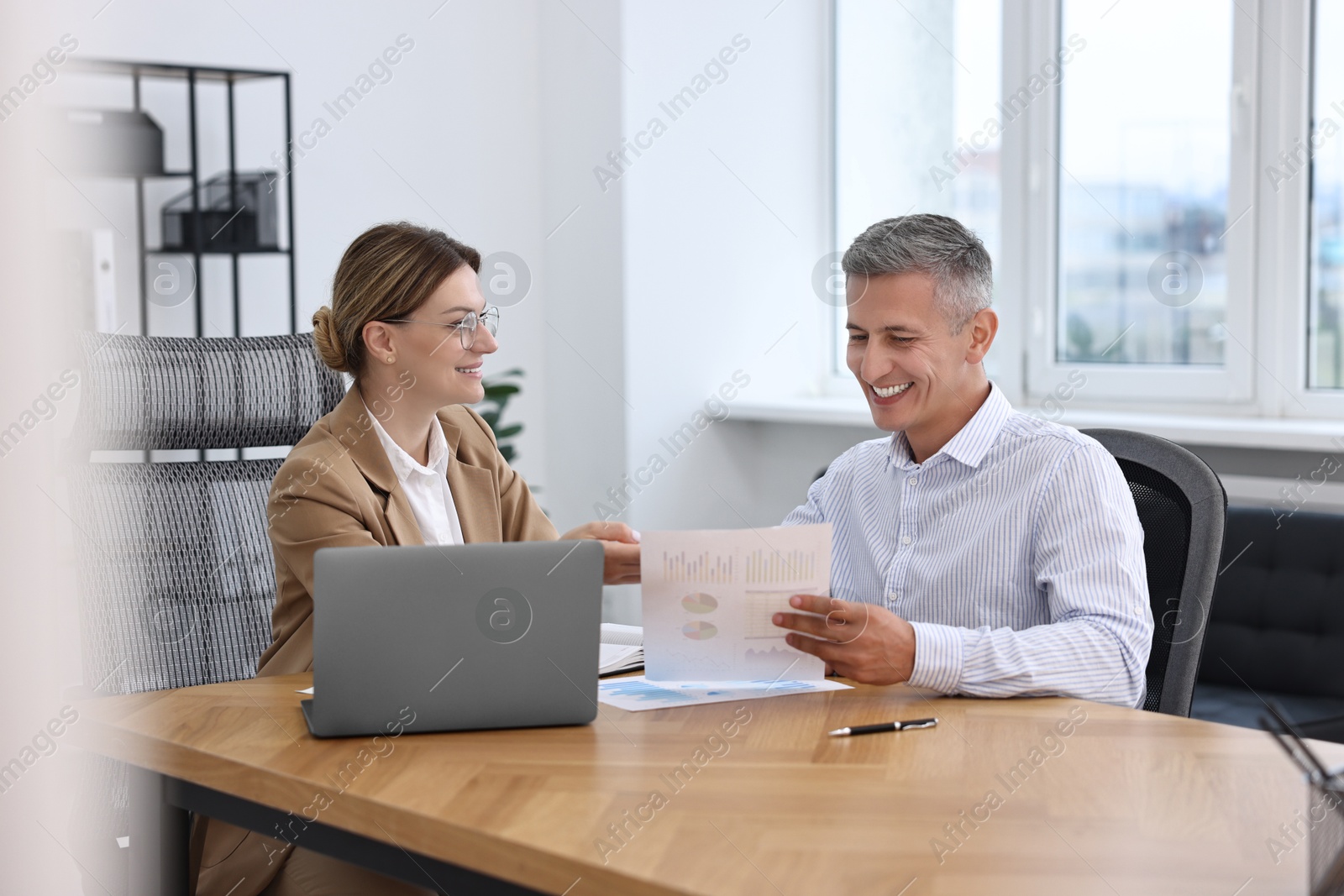 Photo of Banker working with client at wooden table in office