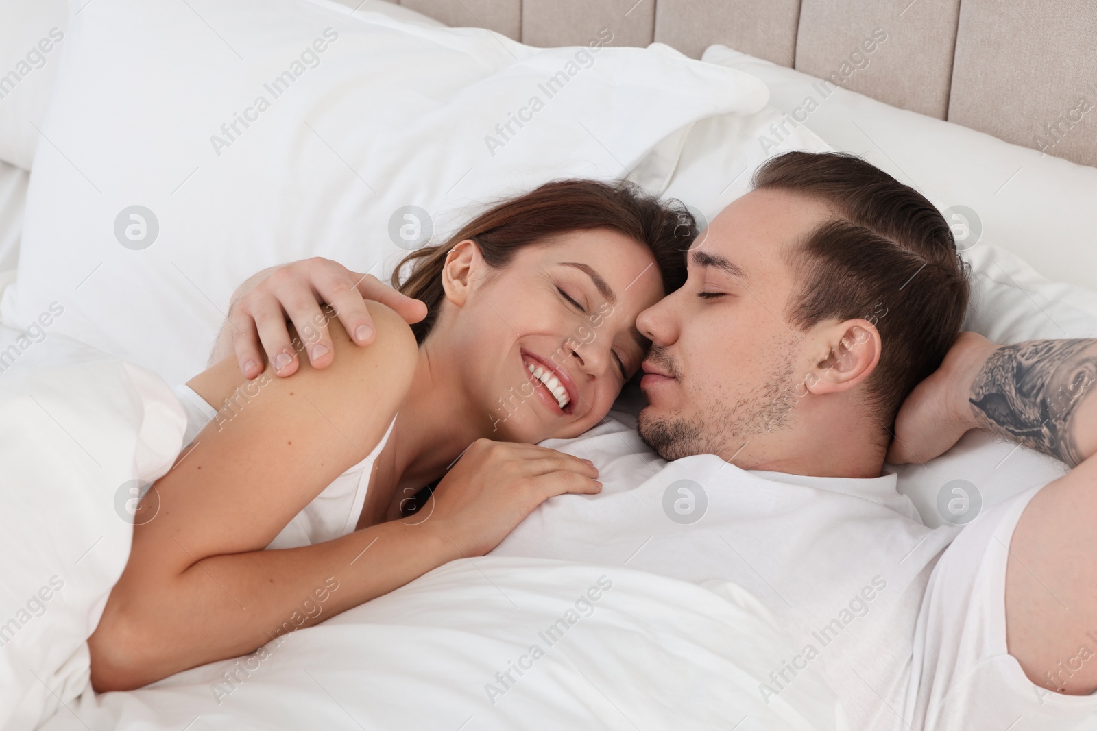 Photo of Happy couple lying on bed at home