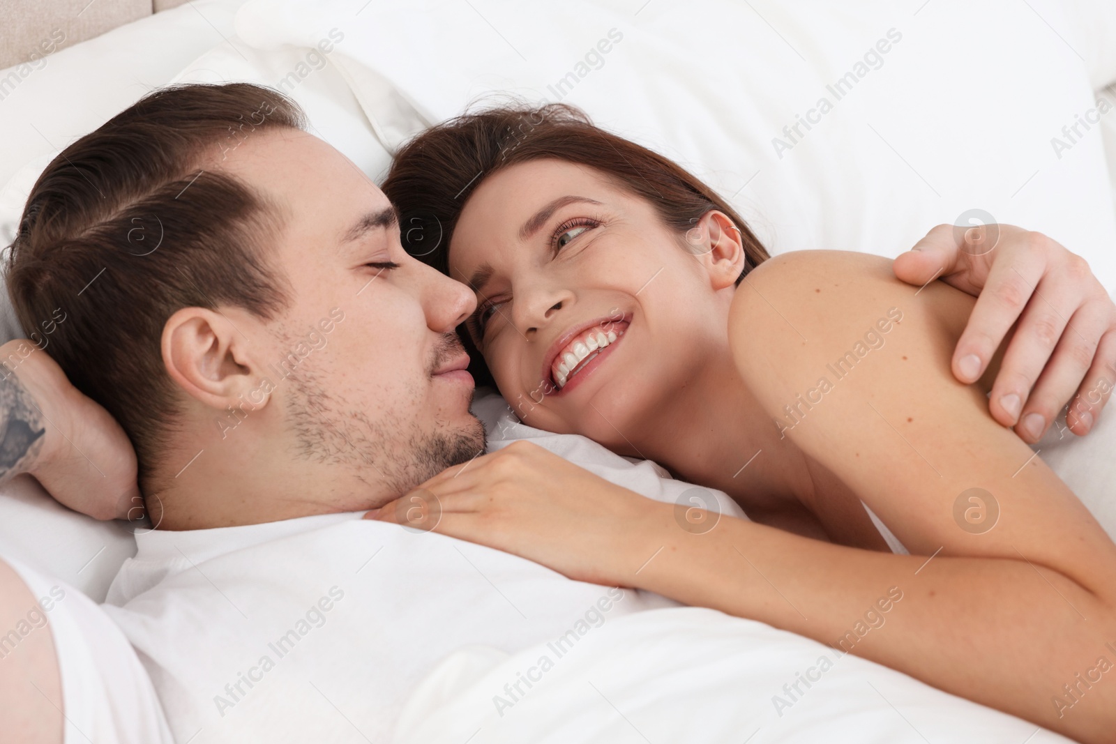 Photo of Happy couple lying on bed at home