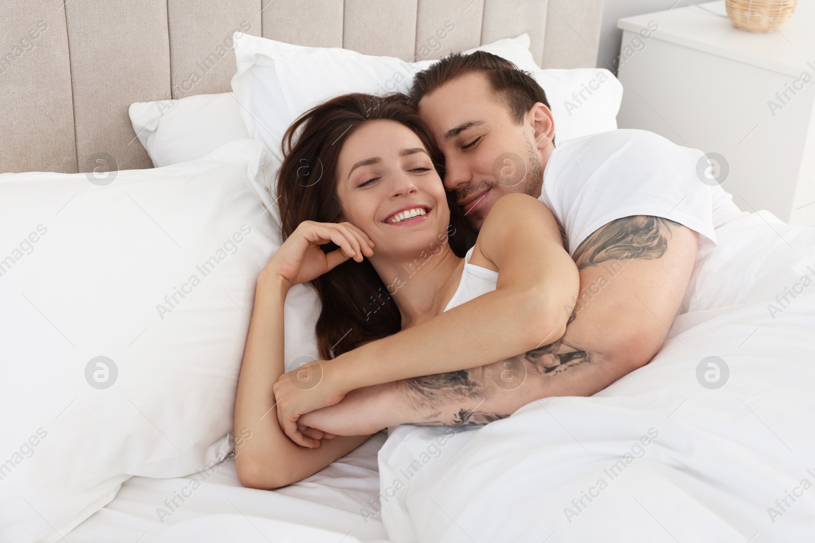 Photo of Happy couple lying in bed at home