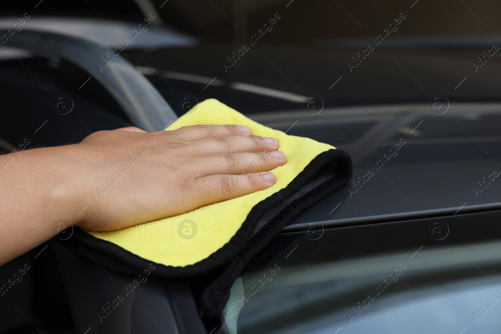 Photo of Man cleaning car with yellow rag, closeup