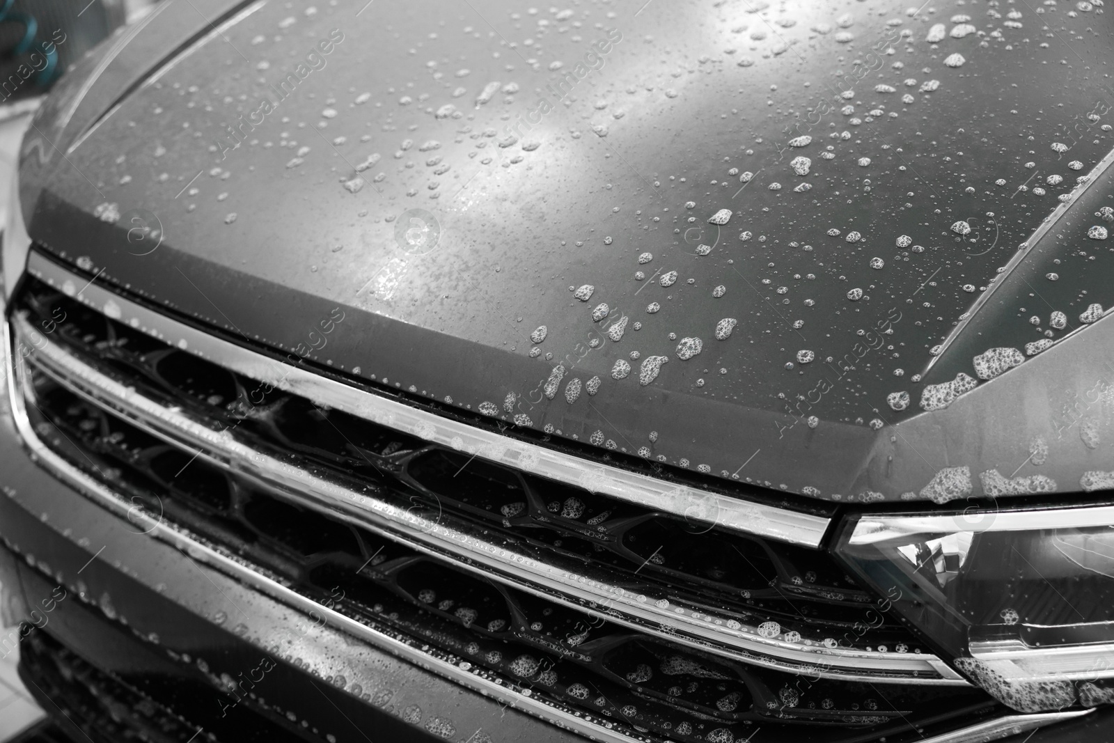 Photo of Auto covered with cleaning foam at car wash, closeup