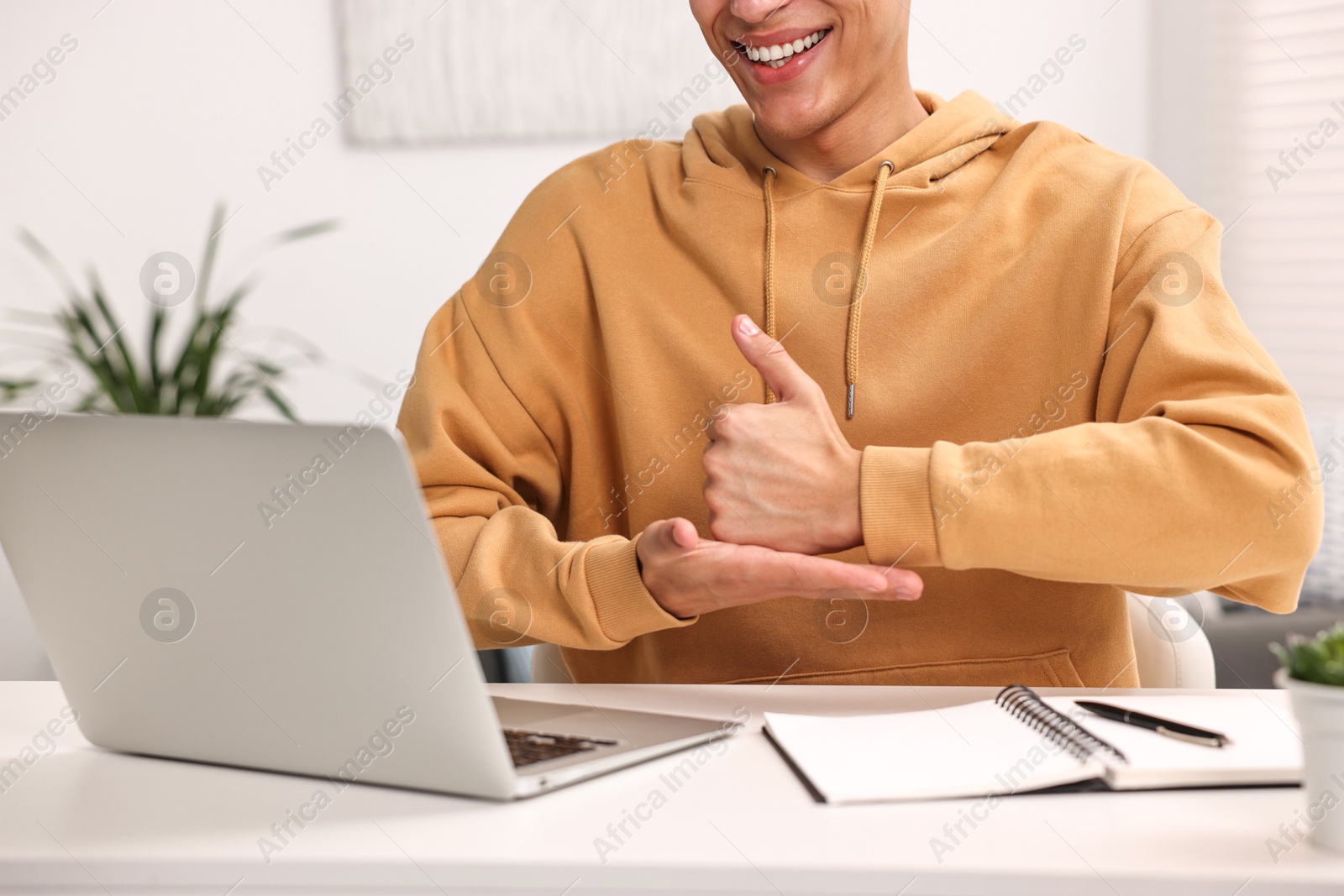 Photo of Young man using sign language during video call indoors, closeup