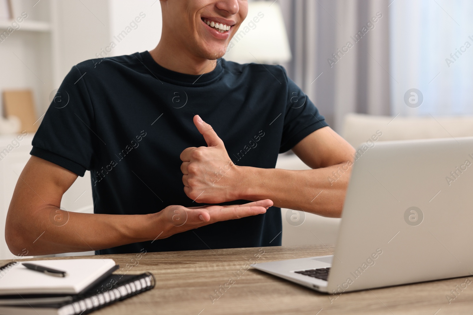 Photo of Young man using sign language during video call indoors, closeup