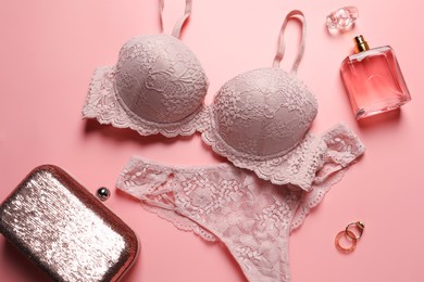 Elegant lace women's underwear, jewellery, bag and perfume on pink background, flat lay