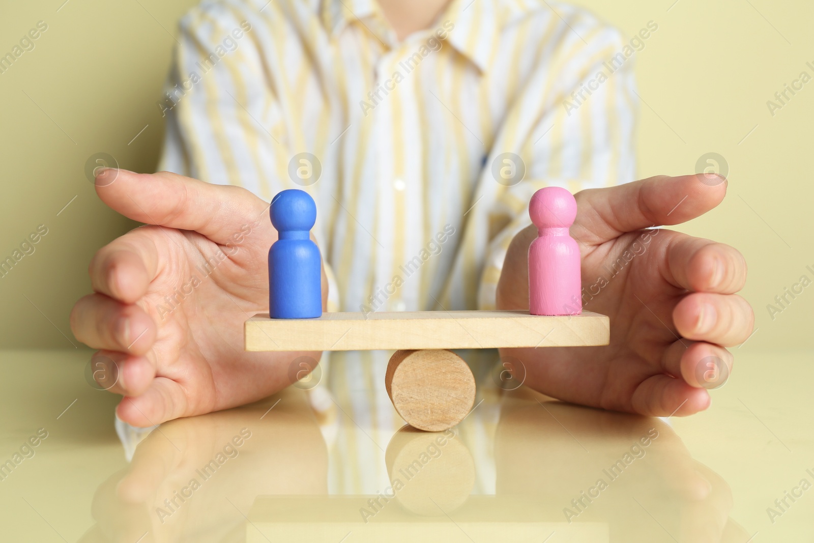 Photo of Gender equality concept. Woman with male and female figures on scales against light yellow background, closeup