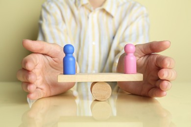 Photo of Gender equality concept. Woman with male and female figures on scales against light yellow background, closeup