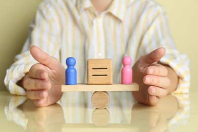 Photo of Gender equality concept. Woman with male and female figures on scales against light yellow background, closeup