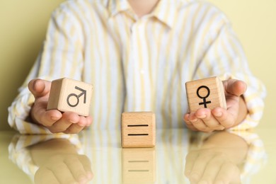 Photo of Gender equality concept. Woman with wooden cubes of male and female symbols at table, closeup