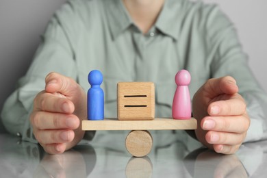 Photo of Gender equality concept. Woman with male and female figures on scales at grey table, closeup