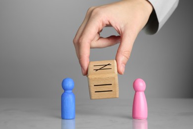 Gender equality concept. Woman with male and female figures at grey table, closeup