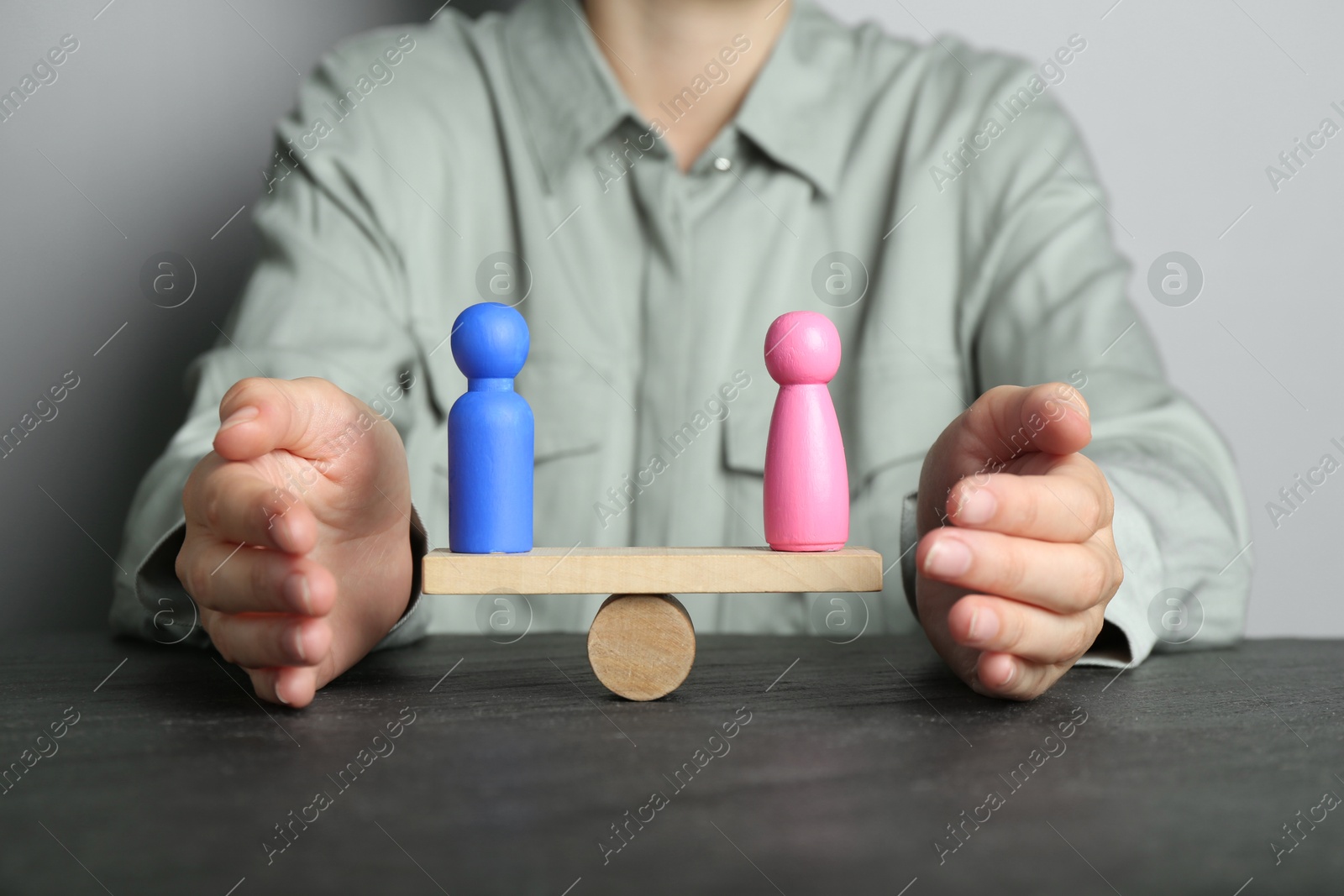 Photo of Gender equality concept. Woman with male and female figures on scales at dark table, closeup