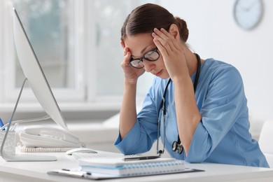 Tired nurse at white table in clinic