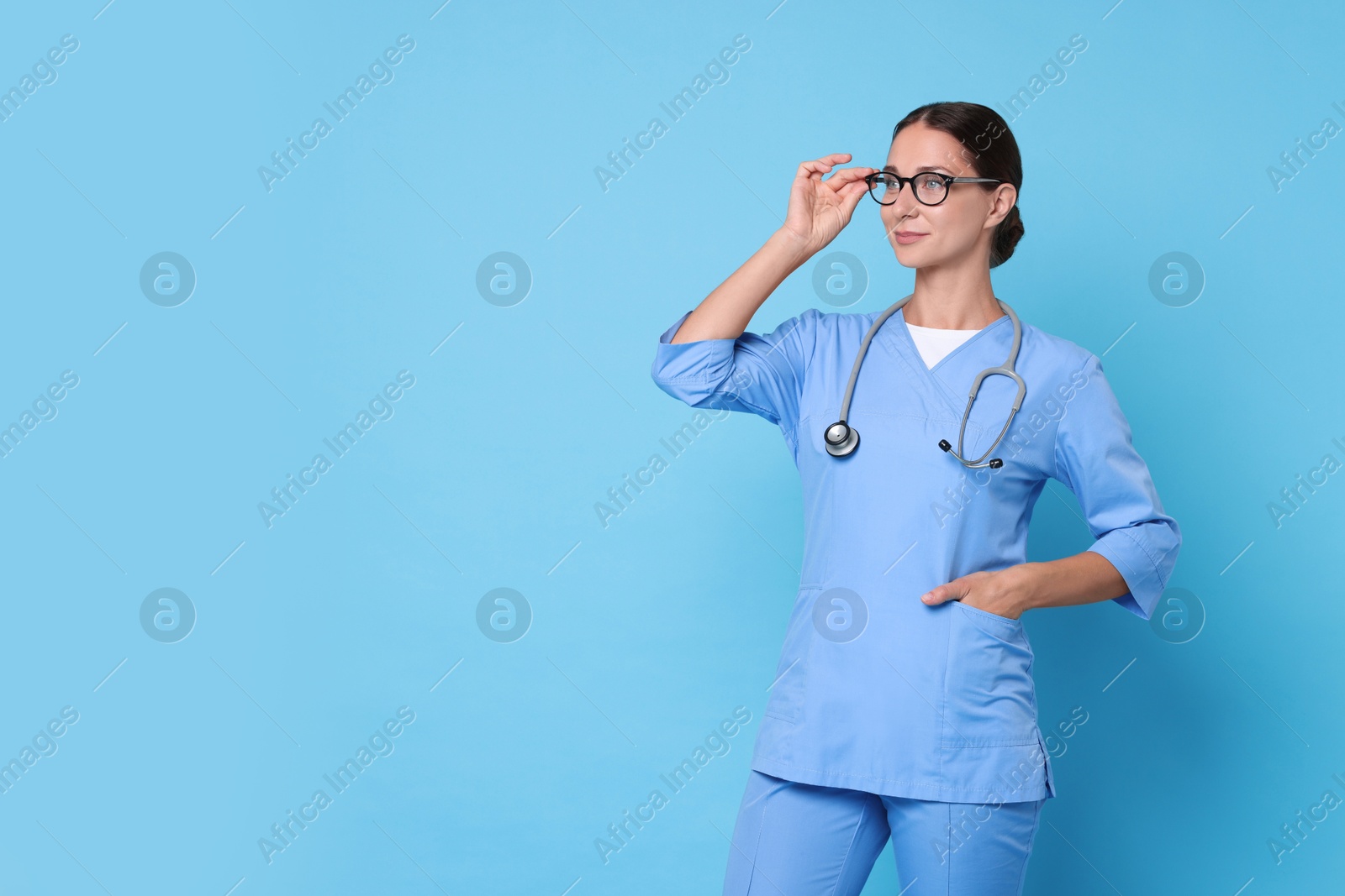 Photo of Nurse in medical uniform with stethoscope on light blue background, space for text