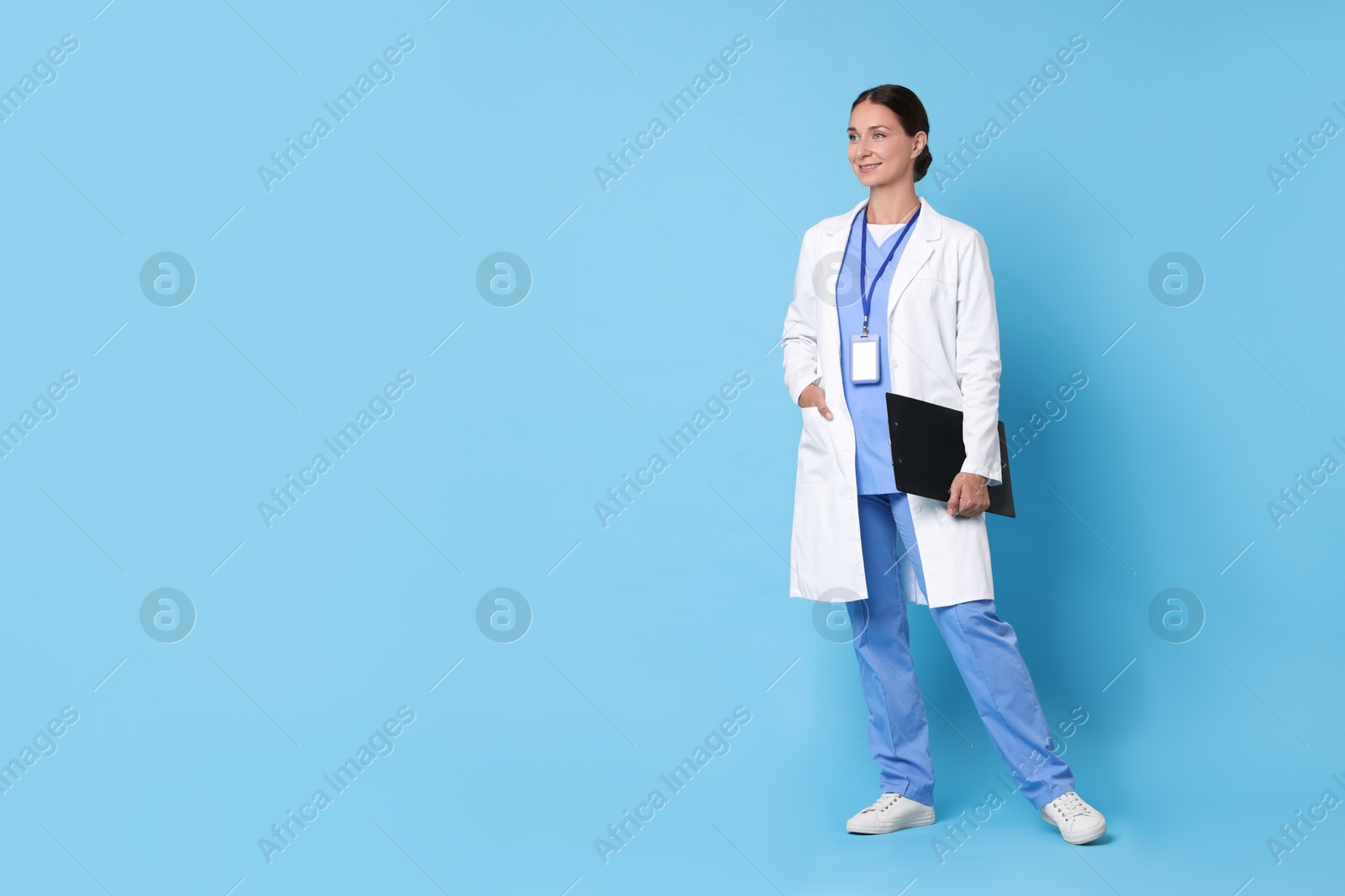 Photo of Nurse in medical uniform with clipboard on light blue background, space for text