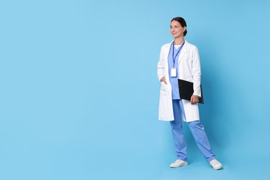 Photo of Nurse in medical uniform with clipboard on light blue background, space for text