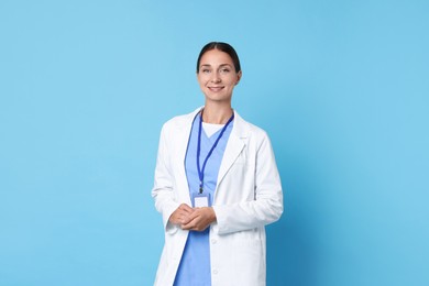 Nurse in medical uniform with badge on light blue background