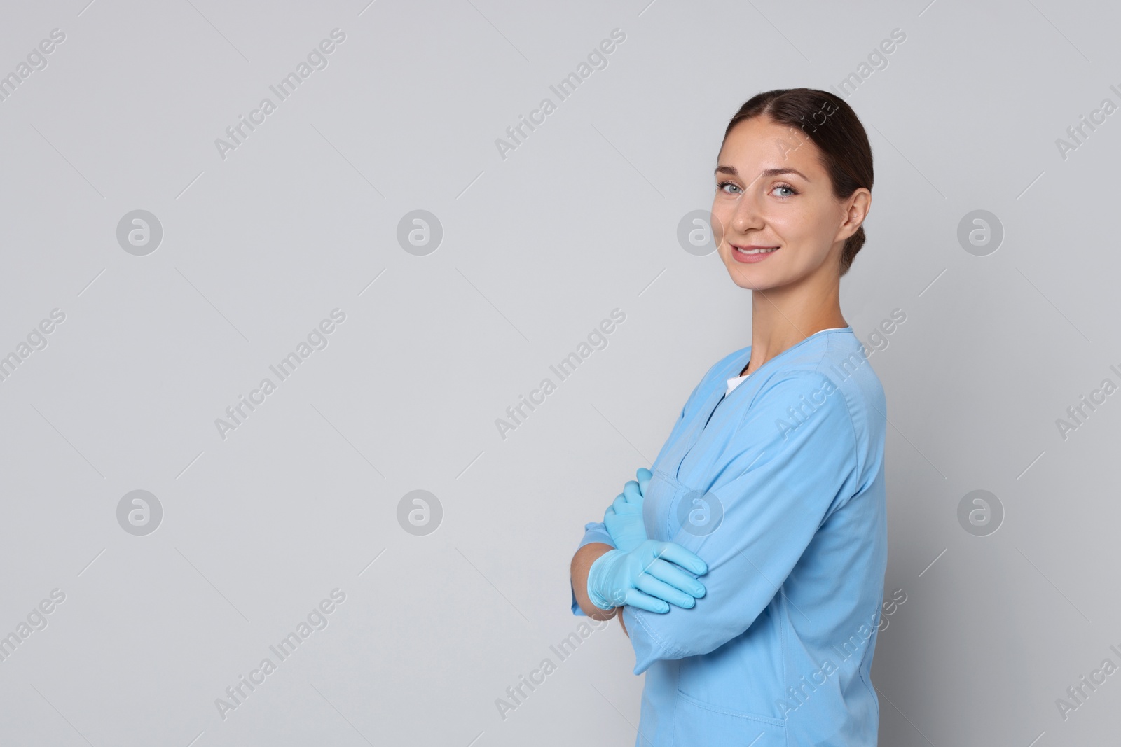 Photo of Nurse with crossed arms on grey background, space for text