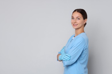 Nurse with crossed arms on grey background, space for text