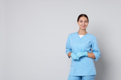 Photo of Nurse in medical uniform on grey background, space for text