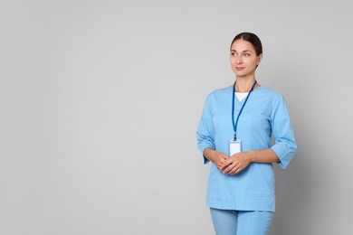 Nurse in medical uniform with stethoscope and clipboard on grey background, space for text