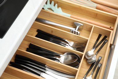 Photo of Box with cutlery in drawer, closeup. Kitchen utensils storage