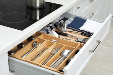 Photo of Box with cutlery in drawer, closeup. Kitchen utensils storage