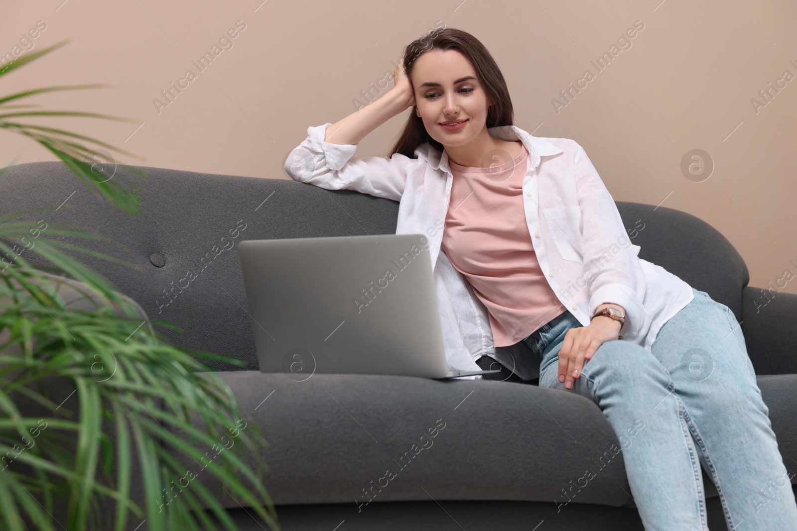 Photo of Beautiful woman looking at laptop on sofa at home. Break time