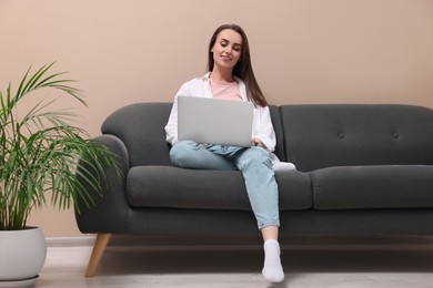 Smiling woman with laptop on sofa at home