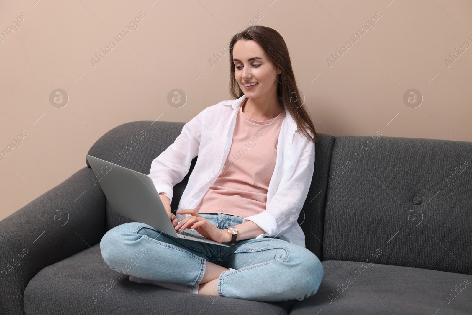 Photo of Smiling woman with laptop on sofa at home