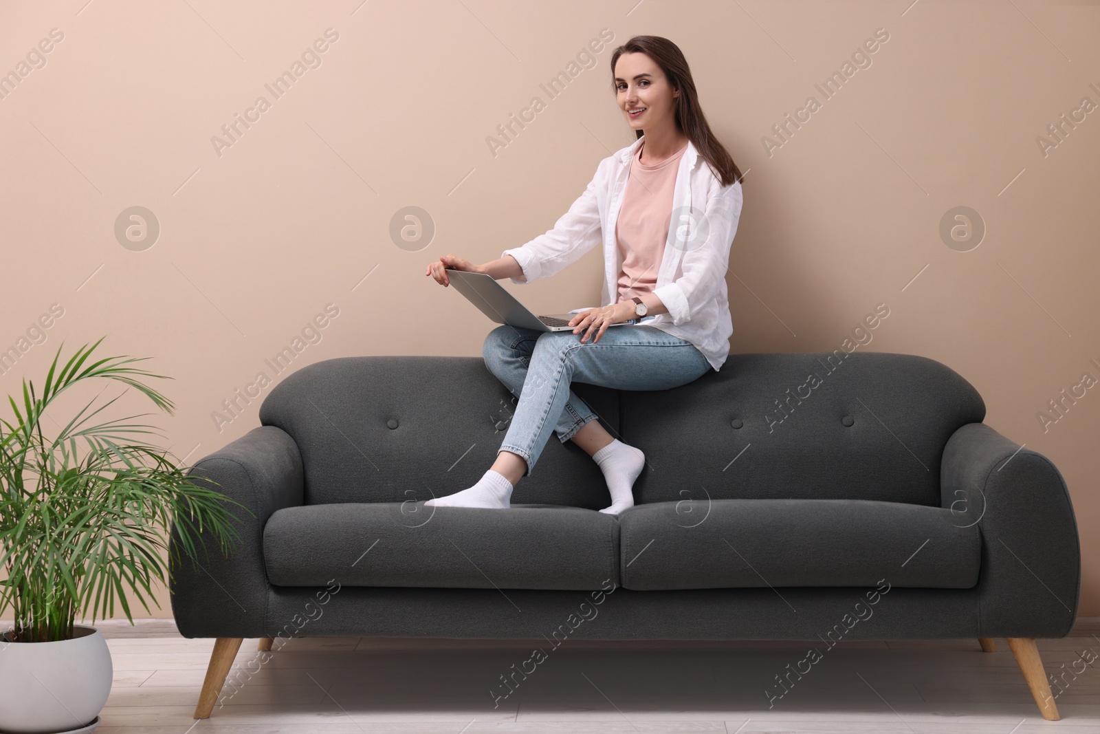 Photo of Smiling woman with laptop on sofa at home