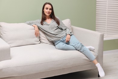 Photo of Smiling woman relaxing on sofa at home