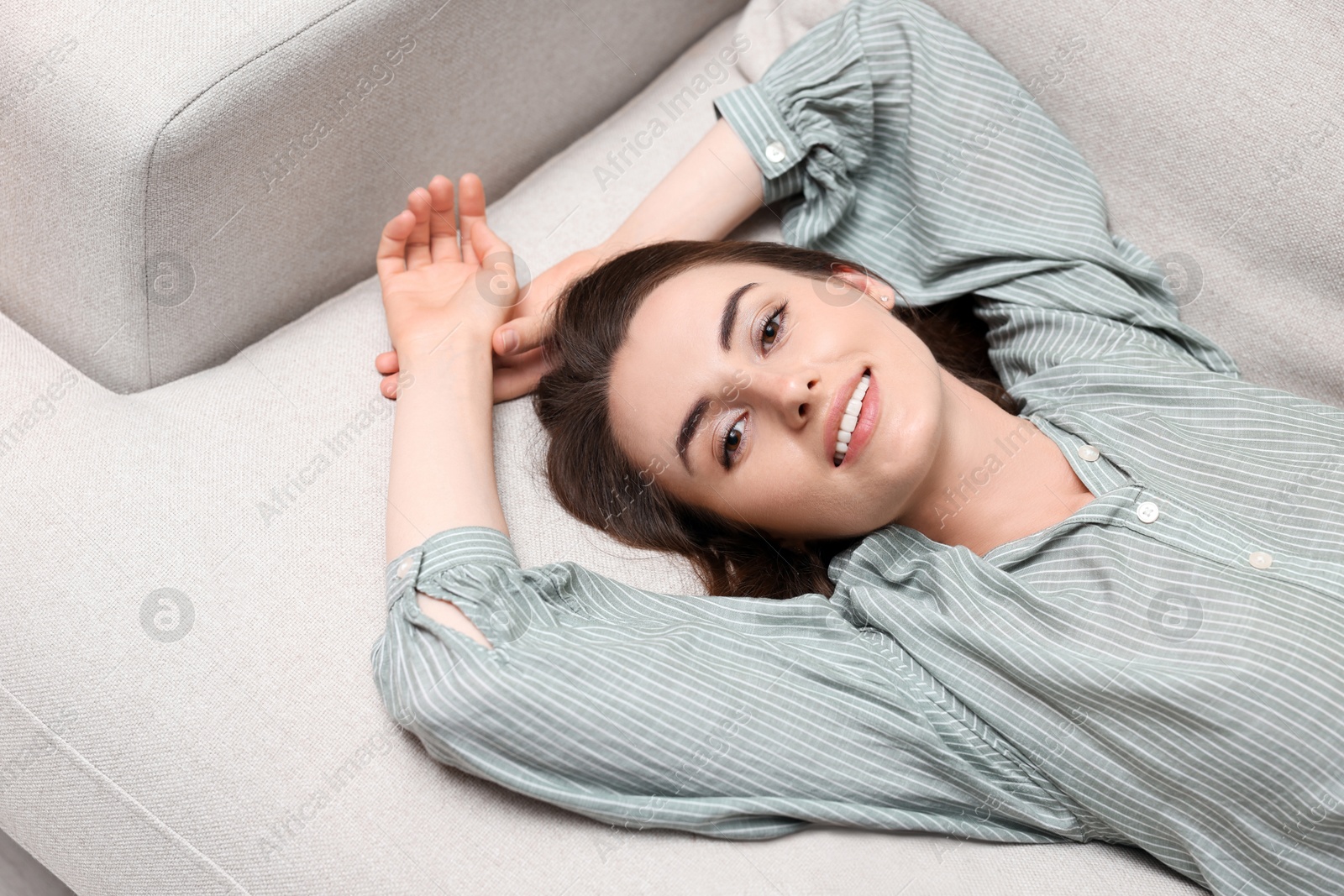 Photo of Smiling woman relaxing on sofa, above view